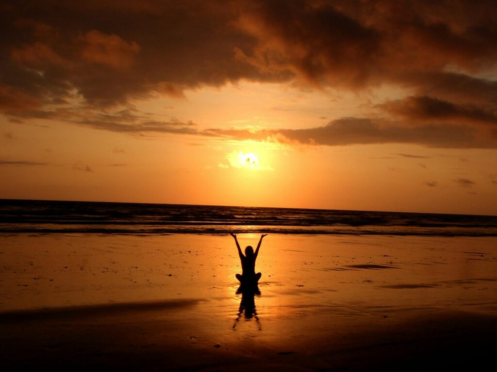 a woman happy on a beach with a beautiful sunet